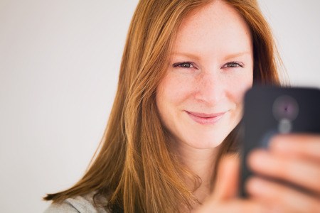 Smiling young woman taking a picture of herself or having a video conversation on her mobile phone.